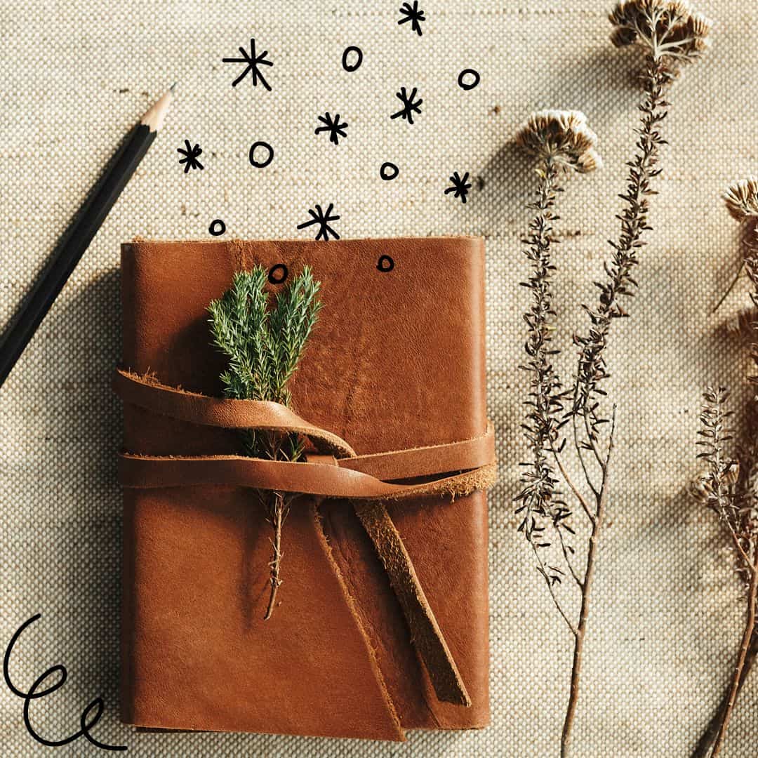 a leather journal with dried flowers near by